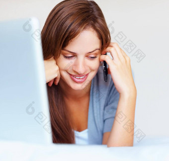 快乐女人前面移动PC床上说话手机可爱的高加索人女人说话手机说谎前面移动PC床上