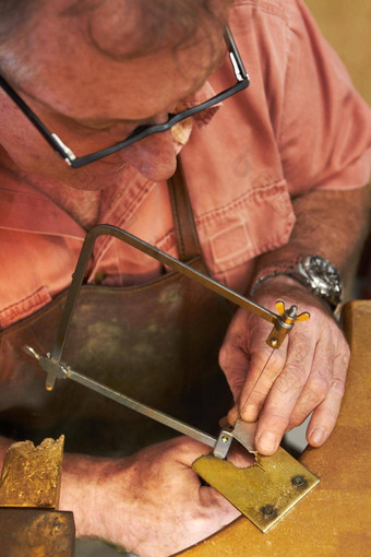 小心翼翼地切割形状珠宝制造业前视图戈德史密斯一块金属