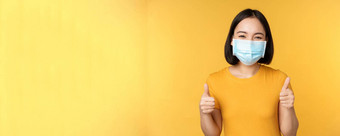 微笑亚洲女人医疗脸面具显示拇指批准推荐smth站黄色的背景