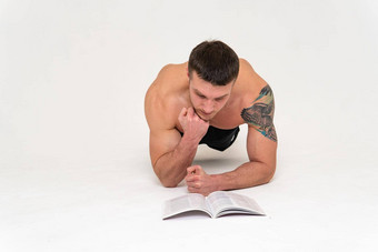 健美运动员读取书白色背景孤立的底头手男人。年轻的阅读运动健身肌肉孤立的健身房摆姿势如此