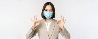 冠状病毒工作场所概念图像亚洲女售货员公司工人医疗面具显示标志微笑很高兴白色背景