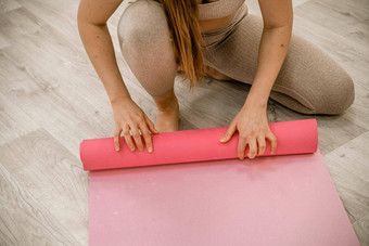 瑜伽首页女人卷粉红色的锻炼席生活房间开始温暖的冥想Zen生活方式生活房间公寓