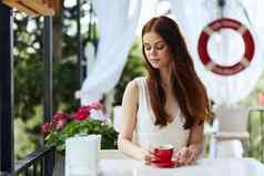 美丽的女人坐着户外咖啡馆街喝咖啡不变的