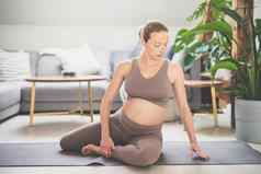 年轻的美丽的怀孕了女人培训普拉提首页生活房间健康的生活方式活跃的怀孕母亲概念