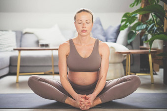 年轻的美丽的怀孕了女人练习瑜伽首页生活房间母亲怀孕健康的生活方式瑜伽概念