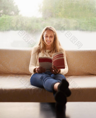 享受<strong>好</strong>书拍摄有吸引力的年轻的女人阅<strong>读书</strong>坐着沙发首页
