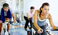女人练习速度自行车健身房美丽的女人工作静止的自行车健身房