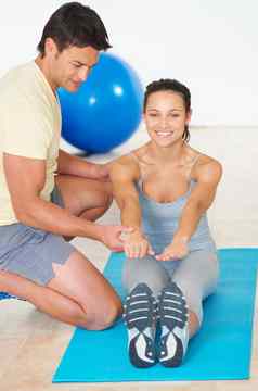 触摸脚趾健身教练显示年轻的女人锻炼