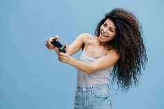 在线游戏概念喜出望外美丽的卷曲的拉丁夫人持有游戏垫脸玩很酷的战斗相机游戏配件品牌工作室拍摄孤立的蓝色的背景