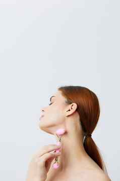 美丽的女人粉红色的石英辊刮板皮肤护理按摩只肩膀孤立的背景