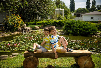 哥哥男孩坐着板凳上公园和平湖水莉莉罗马式建筑孩子们放松自然热夏天一天