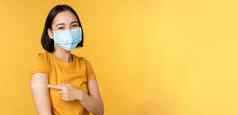 疫苗接种科维德流感大流行概念微笑亚洲女人医疗脸面具显示肩膀乐队援助接种疫苗冠状病毒黄色的背景