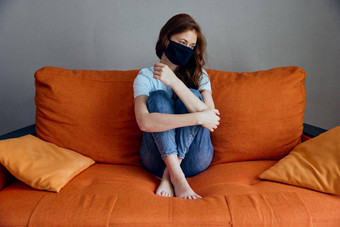 伤心女人坐着橙色沙发首页保护面具检疫