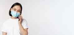 健康科维德概念微笑亚洲女孩医疗脸面具会说话的电话回答移动调用站白色背景