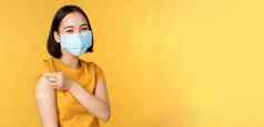 疫苗接种科维德流感大流行概念微笑亚洲女人医疗脸面具显示肩膀乐队援助接种疫苗冠状病毒黄色的背景
