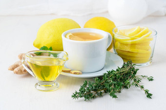 人受欢迎的方法治疗感冒杯茶片柠檬姜薄荷蜂蜜草本植物柠檬一半白色背景一边视图