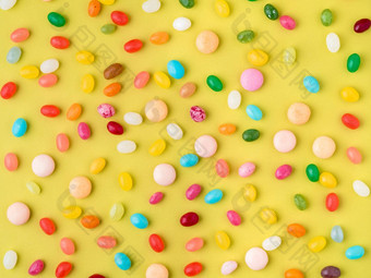 分散色彩斑斓的糖果糖果棒棒糖明亮的黄色的背景前视图