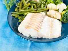 角煮熟的海鱼鳕鱼西兰花绿色豆子菜花蓝色的板一边视图关闭健康的饮食菜适当的营养