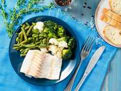 烤海鱼鳕鱼角蔬菜西兰花绿色豆子菜花蓝色的板面包蓝色的餐巾木背景前视图适当的饮食