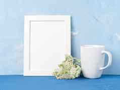 白色杯子茶咖啡框架花花束蓝色的表格相反蓝色的混凝土墙模拟空空间