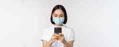 健康科维德移动概念年轻的亚洲女人医疗脸面具智能手机屏幕电话应用程序购物在线白色背景