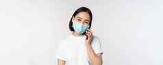 健康科维德概念微笑亚洲女孩医疗脸面具会说话的电话回答移动调用站白色背景