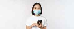 健康科维德概念亚洲女孩医疗脸面具移动电话应用程序检疫站白色背景