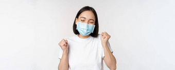 科维德医疗保健医疗概念热情的亚洲女人医疗脸面具跳舞庆祝赢得实现目标站白色背景