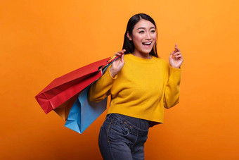 <strong>喜出望外</strong>兴奋美丽的亚洲女人携带购物袋出口商店穿黄色的毛衣