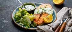 健康的食物餐煮熟的烤大马哈鱼牛排白色莳萝酱汁绿色沙拉树叶