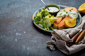 健康的食物餐煮熟的烤大马哈鱼牛排白色莳萝酱汁绿色沙拉树叶