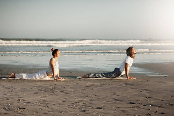 气氛区域添加瑜伽拍摄年轻的夫妇练习瑜伽海滩