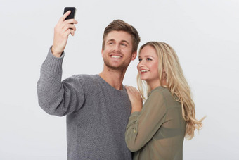 更紧密的工作室肖像快乐年轻的夫妇采取肖像相机电话