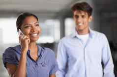 促进伟大的沟通技能年轻的女商人会说话的电话的同事背景