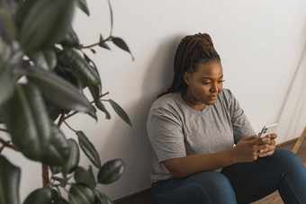 肖像非洲美国女学生穿着随便持有移动电话打字消息沟通朋友社会网络高互联网连接