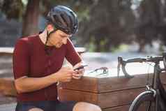 男人。现代智能手机在户外骑自行车