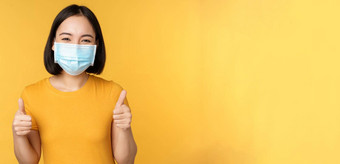 微笑亚洲女人医疗脸面具显示拇指批准推荐smth站黄色的背景