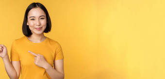 微笑亚洲女人指出手指左显示广告空复制空间站黄色的背景