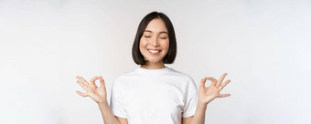 肖像年轻的亚洲女人冥想微笑很高兴实践瑜伽关闭眼睛冥想呼吸平静站白色背景
