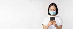 健康科维德移动概念年轻的亚洲女人医疗脸面具智能手机屏幕电话应用程序购物在线白色背景