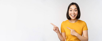 肖像微笑亚洲浅黑肤色的女人女孩黄色的T恤指出手指左显示复制空间促销交易展示横幅站白色背景