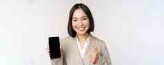微笑亚洲女人显示智能手机屏幕拇指企业人演示了移动电话应用程序接口站白色背景