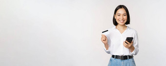 在线购物概念图像年轻的亚洲现代女人持有信贷卡智能手机购买智能手机应用程序支付<strong>非接触</strong>式站白色背景