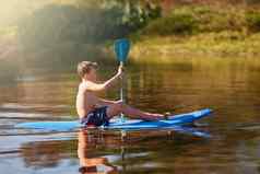 夏季流拍摄十几岁的男孩划船皮艇湖