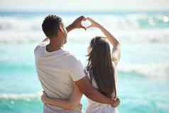 爱运行更深层次的海洋拍摄年轻的夫妇使心手势手海滩