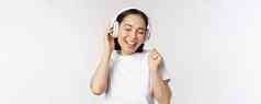 现代亚洲女孩跳舞听音乐耳机微笑快乐站T恤白色背景