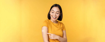 疫苗接种科维德流感大流行概念快乐健康的亚洲女孩指出肩膀乐队援助接种疫苗冠状病毒黄色的背景