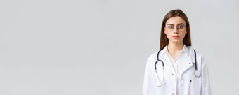 医疗保健工人医学保险科维德流感大流行概念严肃的表情聪明的专业医生护士白色实习医生风云听诊器相机确定灰色背景