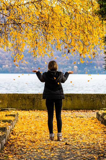 回来视图女人享受秋天扔下降叶子秋天小巷秋天景观橙色树叶公园orsova罗马尼亚