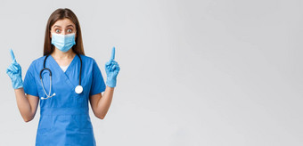 科维德防止病毒健康医疗保健工人概念惊讶好奇的女护士蓝色的实习医生风云个人保护设备指出手指发现有趣的新闻